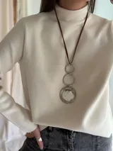 Collar largo con cordón marrón, dije circular plateado con centro de guampa y aros de acero.