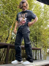 Pantalón negro de gabardina, corte ancho tipo carpenter, con costuras blancas contrastantes.