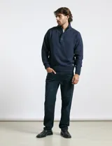 Sweater de punto color azul marino, con cuello alto, cierre frontal parcial y tapeta con botones. Presenta mangas raglán y puños y ruedo acanalados.