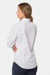 Camisa blanca de corte entallado, manga larga con puños abotonados y cuello clásico. Presenta cierre frontal con botones ocultos bajo una tapeta.