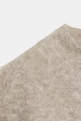 Top de punto color beige, con cuello subido, manga corta y detalle de tejido efecto cepillado.