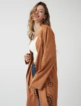 Chaqueta larga color marrón, de símil gamuza calada con diseño de flores y puntos. Tiene silueta abierta y mangas largas de corte recto.