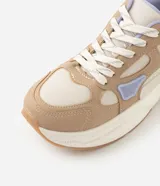 Championes de estilo urbano y deportivo de la marca Satinato, modelo jogging, confeccionados en poliuretano y poliéster en tonos beige, tostado y lila. Presentan una suela robusta texturizada y detalles en malla respirable.