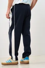Pantalón de jogging azul marino con cintura elástica, bolsillos laterales y una franja blanca gruesa a lo largo de la pierna.
