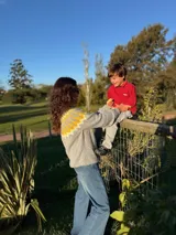 Sweater tejido a mano en mohair, de cuello redondo y manga larga. Presenta un diseño de canesú con patrón geométrico en tonos amarillo y blanco sobre una base de color marrón.