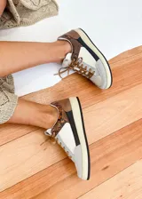 Championes urbanos de cuero vacuno color blanco, con detalles en gris y marrón con estampado animal print. Interior forrado en textil acolchado y cordones marrones.