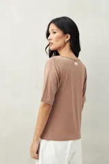 Remera blanca de manga corta con escote asimétrico y detalle de nudo con frunces en el centro del busto.