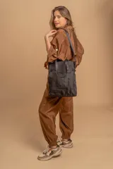 Bolso tipo tote bag de símil cuero color rosa pálido, con asas dobles y detalles de costura en color beige claro. Presenta un bolsillo frontal rectangular aplicado y herrajes metálicos.