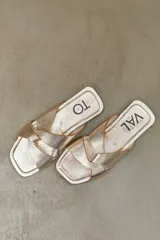 Sandalias doradas con tiras cruzadas y suela plana.