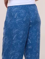 Pantalón palazzo de rayón color azul con estampado paisley blanco, corte amplio, tiro medio-alto con pretina elastizada y aberturas laterales en el puño regulables con lazos.