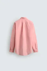 Camisa de corte relajado color celeste, confeccionada en mezcla de algodón y seda. Presenta cuello solapa, cierre frontal de botones, manga larga con puños abotonados y dos bolsillos de plastrón con solapa en el pecho.