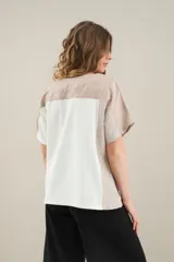 Blusa de lino de diseño contemporáneo, con escote cuadrado y mangas cortas en recortes que combinan distintas texturas. Su propuesta incorpora una franja vertical en contraste que aporta dinamismo y personalidad, mientras que el calce relajado la convierte en una prenda fresca y versátil.