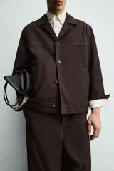 Sobrecamisa de corte regular confeccionada en tejido de mezcla de lyocell y algodón. Presenta cuello con solapas de muesca, cierre frontal con botones, mangas largas con puños abotonados y bolsillos de vivo en la parte frontal.