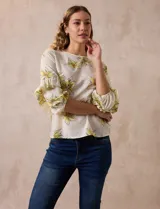 Blusa de gasa color blanco con estampado de flores amarillas, de la marca Sioni. Tiene mangas 3/4 con volados y cuello redondo.