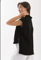 Chaleco tejido de punto con cuello levemente alto y silueta amplia. Presenta un diseño con aberturas laterales y un largo asimétrico, siendo más corto en el frente y más largo en la espalda.