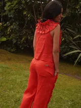Pantalón de lino color beige, con apliques de tela con volados y costuras decorativas que aportan textura y movimiento. Cuenta con diseño de pernera ancha, bolsillos y aberturas laterales.