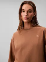 Buzo Calvin Klein de felpa francesa color marrón, con cuello redondo, mangas largas, puños y dobladillo acanalados, y el logo retro de la marca bordado en el pecho.