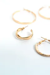 Set de tres pares de aros tipo argolla dorados, de diferentes tamaños y diseños: un par grande de aro fino liso, un par mediano de aro más ancho y liso, y un par pequeño con textura retorcida.