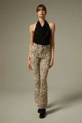 Pantalon tipo jean de tiro alto con corte flare y estampado animal print abstracto en tonos beige y negro. Cuenta con bolsillos funcionales y ruedo deshilachado.