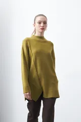 Polera de tejido de punto color verde oliva, con cuello alto, hombros caídos y diseño asimétrico con costura diagonal frontal y abertura en el ruedo.