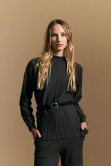 Polera de tejido de punto color marrón, con cuello alto y diseño de líneas verticales en el frente que aportan estructura. Presenta un calce relajado y mangas largas con puños ajustados.