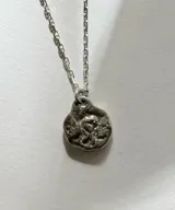 Collar de plata con cadena de eslabones y dije en relieve con forma de querubín alado.