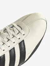 Zapatillas Adidas Tokyo de cuero color crema con detalles en negro, incluyendo las tres tiras laterales y la suela.