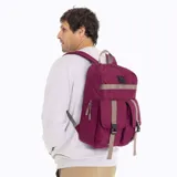 Mochila urbana Merrell de color bordó, confeccionada en poliéster canvas. Cuenta con un compartimento principal con cierre, un bolsillo frontal con dos correas ajustables con hebillas y una cinta horizontal decorativa. Incluye logo de la marca en la parte superior.