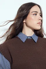 Chaleco tejido sin mangas de color negro, con cuello redondo y diseño de textura sutil. Presenta un corte recto con terminaciones acanaladas en el ruedo y hombros levemente estructurados.