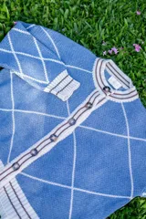 Saco tejido de punto con diseño de rombos en color bordó y naranja, con detalles en lurex. Presenta cuello redondo, cierre frontal con botones y mangas abullonadas con puños acanalados.