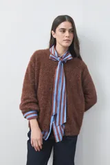 Cardigan de textura suave y efecto fluffy, color beige, con cuello redondo, cierre frontal con botones y puños acanalados.