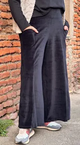 Pantalón tipo palazzo de tiro alto, confeccionado en plush de algodón con textura suave. Presenta un diseño amplio y fluido, con bolsillos laterales y una faja ancha en la cintura que brinda ajuste y comodidad.