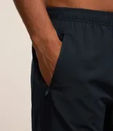 Bermuda deportiva gris con cintura elástica, cordón de ajuste, bolsillos con cremallera, recorte lateral con agujeritos y abertura en el bajo.