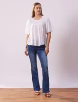 Blusa blanca de gasa marca Zac & Rachel, con frunces en la parte delantera, mangas cortas con puño elastizado, abertura central en la espalda y botón.
