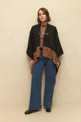 Poncho negro con estampado animal print en el borde inferior y cierre con alamar dorado.
