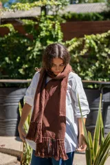 Bufanda tejida en color marrón con diseño de rombos en relieve y terminación con flecos en los extremos. Incluye una etiqueta de cuero sintético con la marca Diversa.