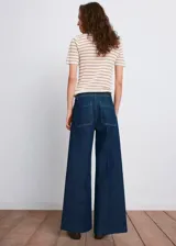 Pantalón wide leg de denim azul oscuro, de tiro alto con trabillas y cierre frontal de cremallera y botón. Presenta bolsillos de parche delanteros.