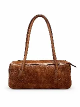 Cartera de cuero tipo baguette, con formato alargado, acabado de efecto vintage, dos asas largas para llevar al hombro y cierre superior.