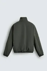 Cazadora de corte relajado confeccionada en tejido técnico color verde oscuro, con interior de borreguillo, cuello subido, cierre frontal de cremallera y bolsillos laterales con cremallera.