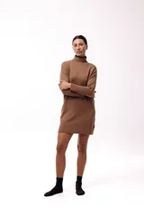Vestido corto de tejido de punto color marrón, con cuello alto y mangas largas. Presenta un diseño de silueta relajada y terminaciones acanaladas en puños y ruedo.