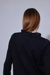 Blusa de estilo romántico con frente de lino y espalda y mangas de algodón con elastano. Presenta un diseño con mini volados en la pechera, cuello redondo y cierre frontal con botones.