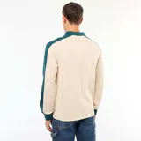 Remera polo de manga larga con diseño bicolor, combinando cuerpo en color beige con cuello, tapeta de botones y mangas en color verde oscuro.