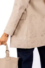 Blazer color beige con diseño bordado tono sobre tono en mangas y parte inferior. Presenta corte recto, solapas clásicas, cierre frontal con un botón y bolsillos laterales con solapa.