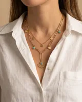 Collar doble de acero con baño de oro, compuesto por una cadena de eslabones alargados y una cadena fina con dijes colgantes de corazones, círculos y un dije central en forma de ojo turco con diseño de abanico.