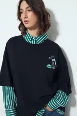 Remera blanca de manga corta, cuello redondo y calce relajado. Presenta un pequeño estampado frontal de un perro con un hueso y un estampado grande en la espalda con la frase "WILD HEART" y un diseño gráfico.