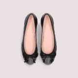 Bailarinas negras de napa acolchada con puntera de charol, lazo negro y tacón de 2.5cm. Suela de goma antideslizante, plantilla de piel y forro de tela.