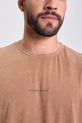 Remera marrón de manga corta con corte oversize y estampa en la espalda con la frase "Each corner of the world has a story to tell".