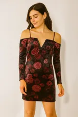Vestido corto de terciopelo negro con estampado de rosas rojas, escote off-shoulder con tirantes finos y mangas largas ajustadas.