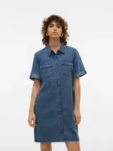 Vestido corto de denim azul de manga corta, con cuello camisero, cierre frontal de botones metálicos y bolsillos delanteros con solapa en el pecho.