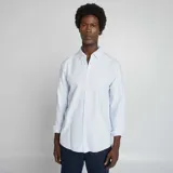 Camisa celeste de corte clásico, con cuello abotonado y mangas largas con puños abotonados.